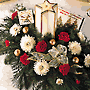 holiday arrangement with a  glowing  star-shaped candle, red and white flowers and Christmas greens