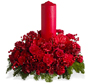 holiday floral arrangement with red candle. Filled with Christmas greens, red carnations, red roses  and ribbon
