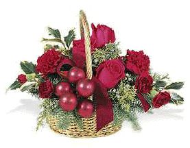 holiday basket arrangement is filled with Christmas greens, red carnations, red roses, red berries and ribbon